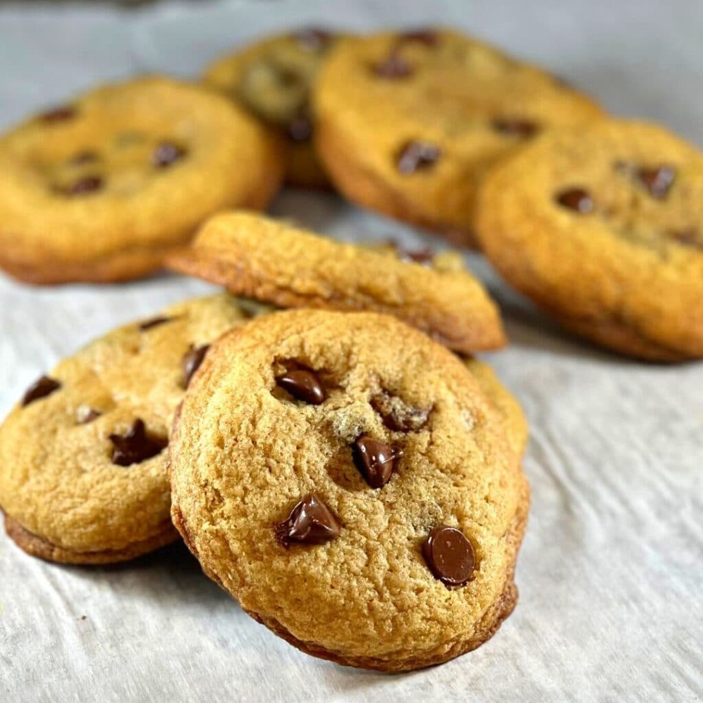 Soft and fluffychewy chocolate chip cookies on a parchment paper lined sheet tray.
