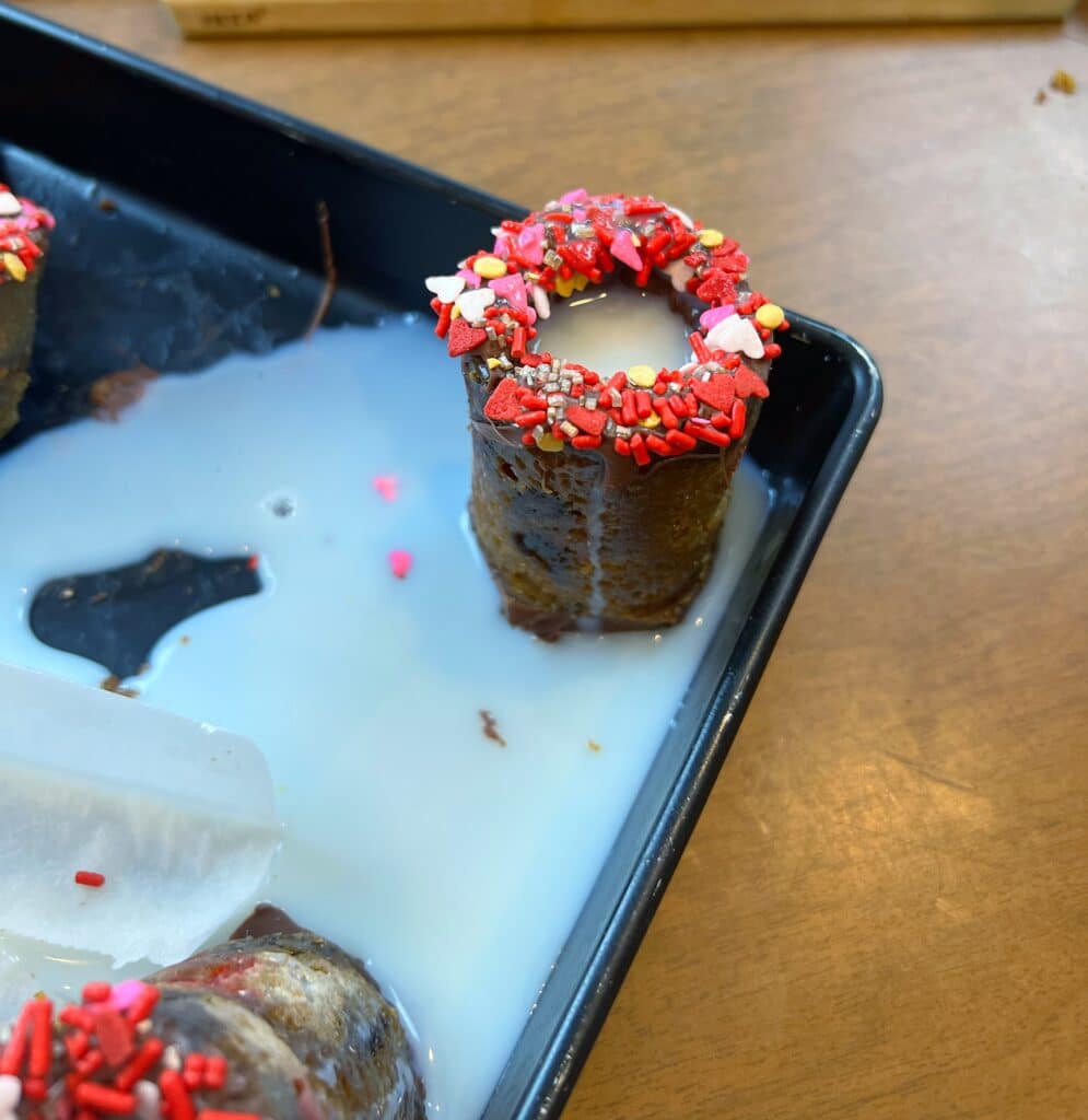 Valentine's Day chocolate chip cookie shots with milk leaking out of it.